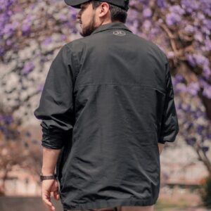 man in black polo shirt and black hat standing near purple flowers during daytime